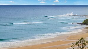 Une plage avec des vagues, un rivage sablonneux et un ciel dégagé.