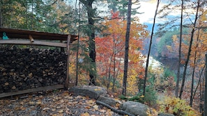 A rustic cabin with a stone wall and a wooden deck overlooking a forested valley. - La Petite Retraite du Lac: Spacious-Gym-2.5 Bath (Rawdon)