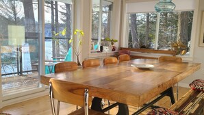 Un comedor con una gran mesa de madera, sillas de metal y bancos.