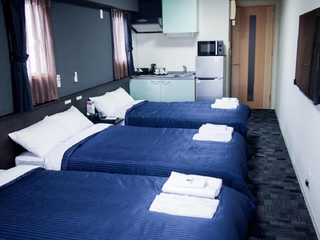 Una habitación de hotel con dos camas, un rincón americano y un microondas.