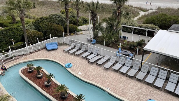 Zona de piscina con sillones de descanso y vistas a la playa.