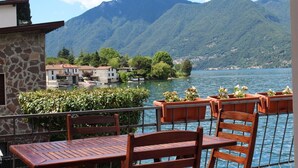 Une terrasse meublée de mobilier en bois, offrant une vue sur un lac et des montagnes.