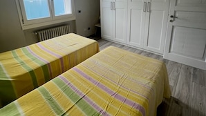 Une chambre avec deux lits, une grande armoire, une fenêtre donnant sur un beau paysage et un plafond avec des poutres en bois.