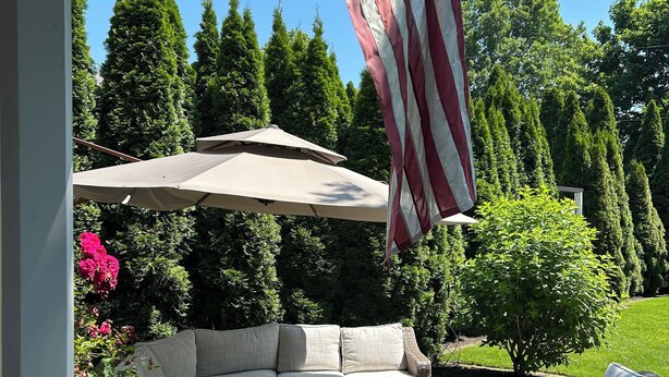 An outdoor patio with a sectional sofa, wicker chairs, and a round table.