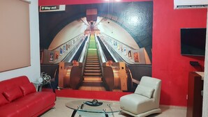 A room with a red couch, a white armchair, a glass coffee table, and a mural of an escalator. - Yikal house. Beautiful house 4 rooms (10 pers), 4 tennis court pools. (38)