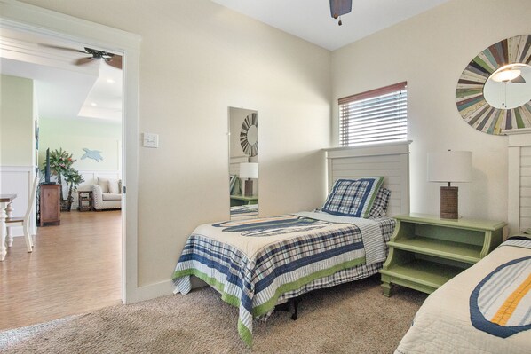 A bedroom with a bed, a nightstand, a mirror, and a window with blinds. - Chompy's Beach Cabin (Bolivar Peninsula)
