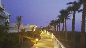 A paved pathway with a railing on one side, leading towards a building with illuminated windows. - The Buddha House Torrox Costa (Torrox Costa)