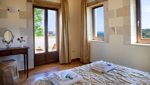 Une chambre à coucher avec un lit, un bureau, un miroir et une fenêtre donnant sur un beau paysage.