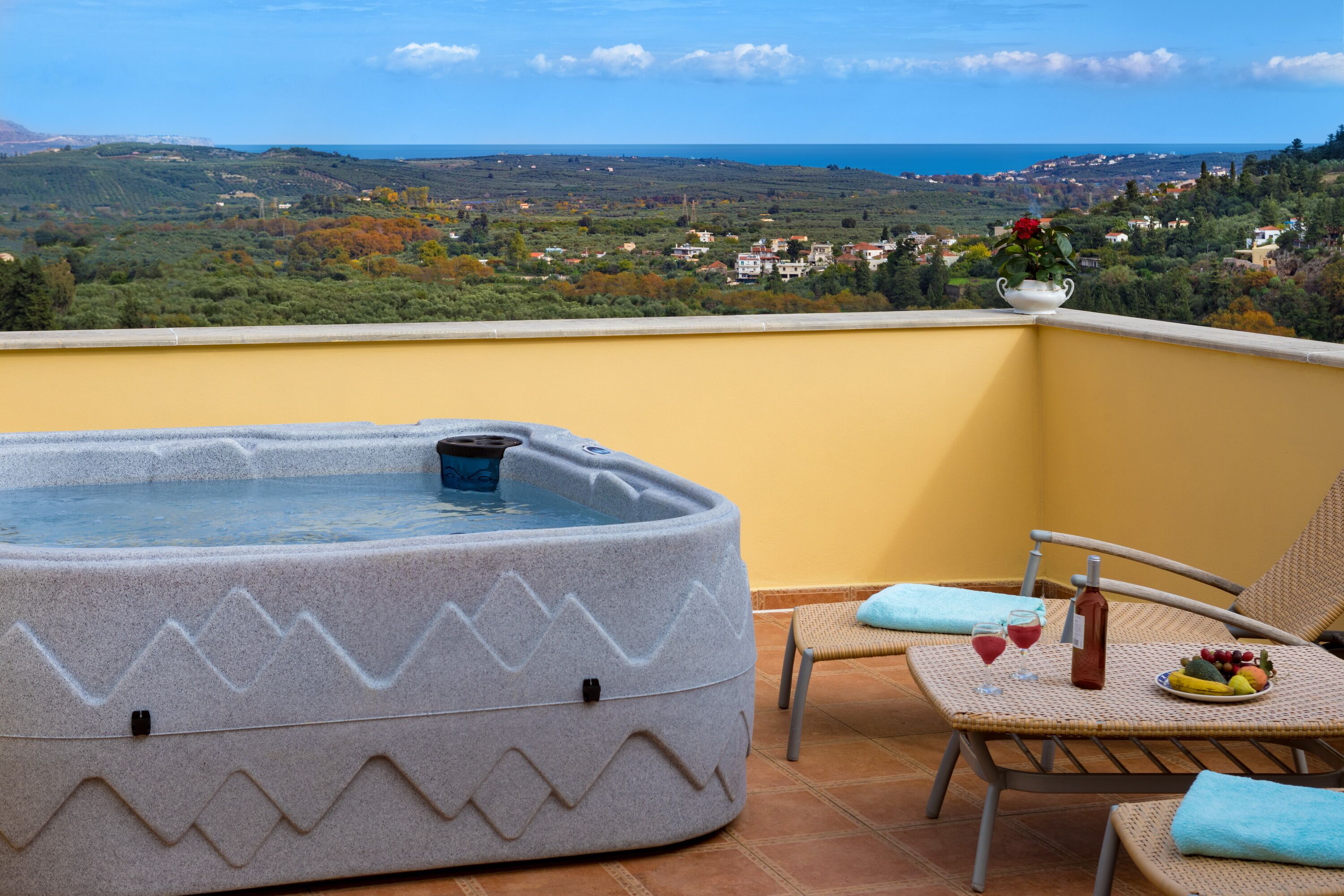 A hot tub on a balcony with a view of a coastal town.