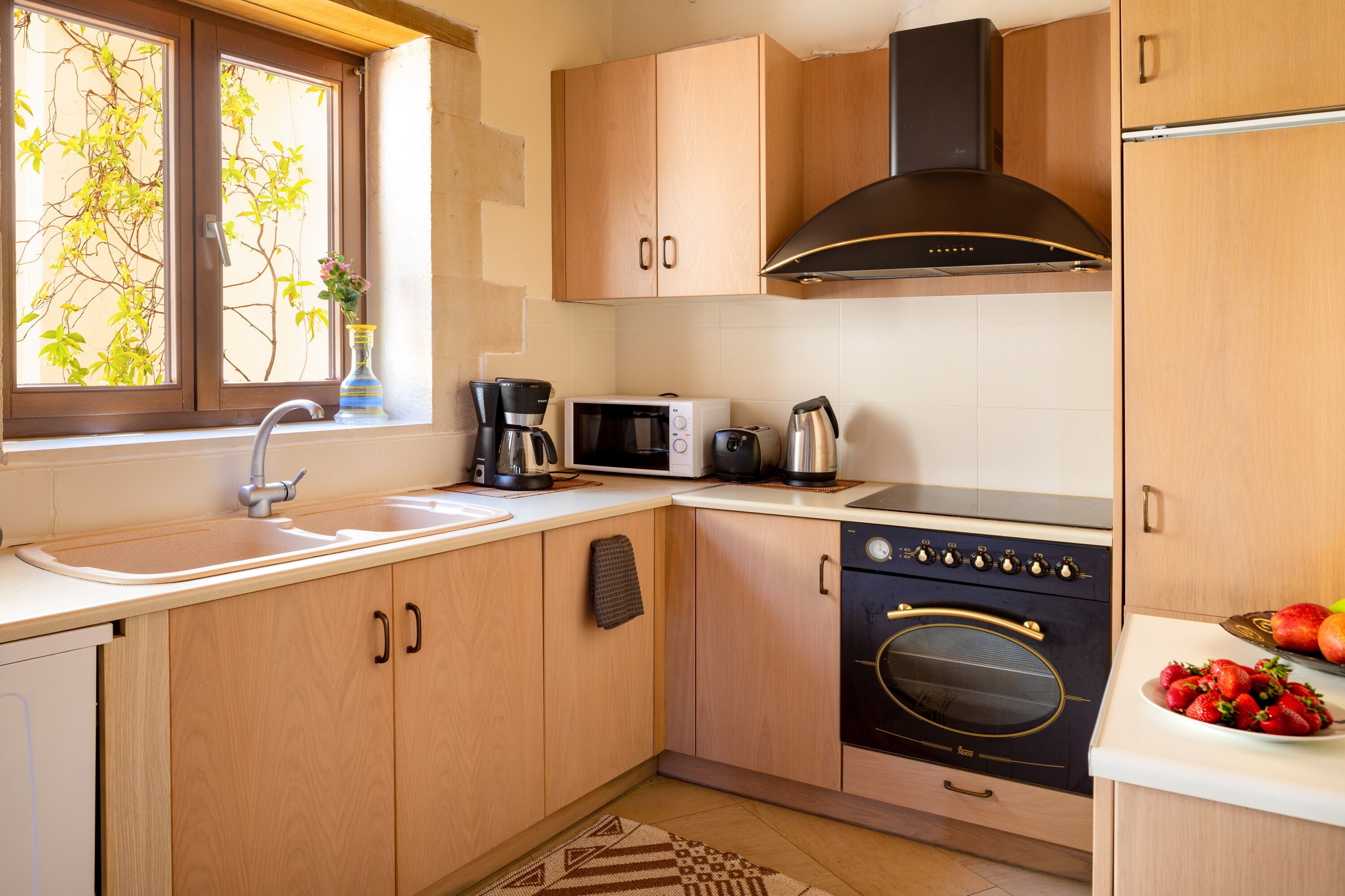 A modern kitchen with wooden cabinets, a stainless steel sink, a microwave, a coffee maker, and a stove.