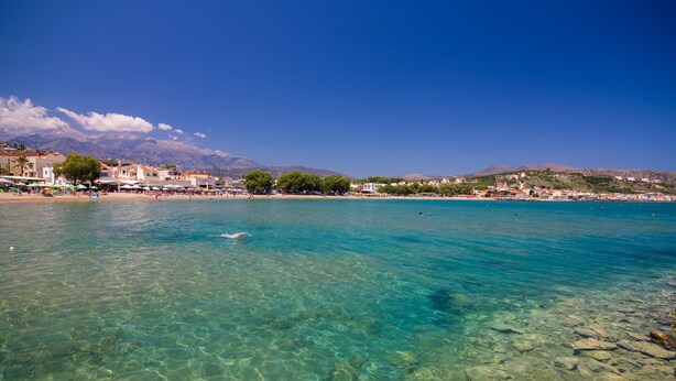 Une ville côtière aux eaux turquoise et limpides, avec un littoral rocheux et des bâtiments qui bordent la plage.
