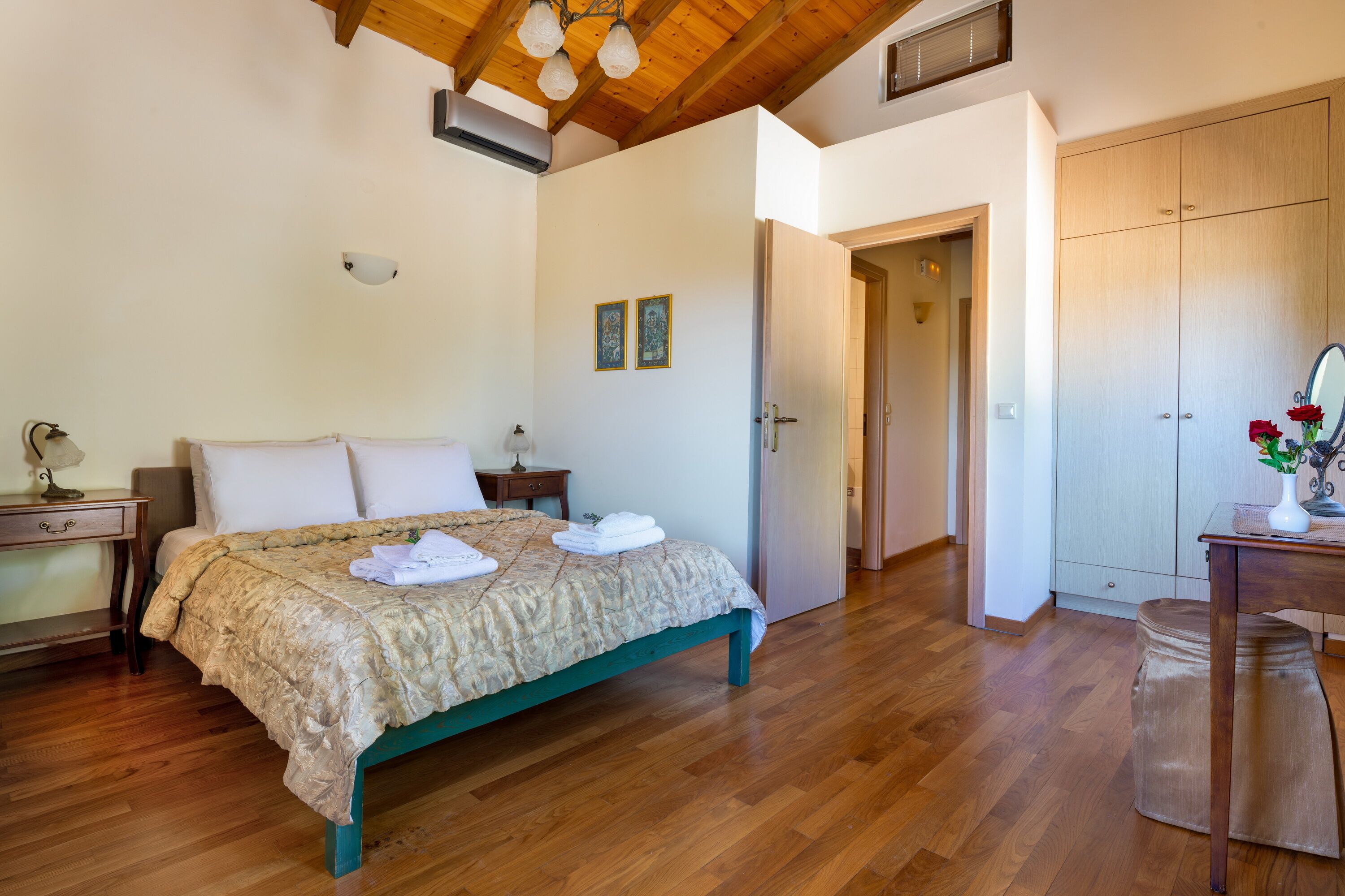 A bedroom with a wooden bed, a nightstand, a dresser, and a door leading to another room.