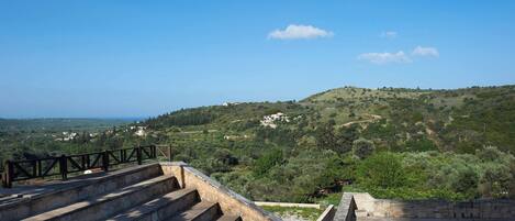 A stone staircase leading to a terrace with a view of a hilly landscape.