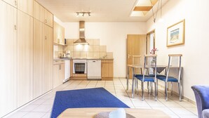 Een moderne keuken met houten kastjes, een vaatwasser en een eethoek met blauwe stoelen.