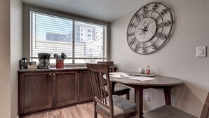A kitchen with wooden cabinets, a dining table with chairs, a large wall clock, and a window with blinds. - See the Valley of the Sun, Arizona State University and Tempe just a short walk. (Tempe)