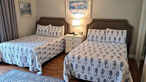 Una cama doble con cabeceras y pieceras a juego, una mesita de noche con lámpara, y un cuadro en la pared.