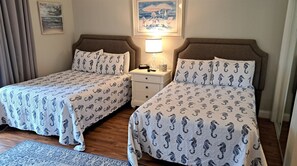 A double bed with matching headboards and footboards, a bedside table with a lamp, and a framed picture on the wall.