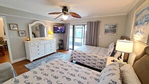 Un dormitorio con cama, cómoda, televisor y ventilador de techo.