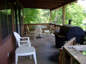 Enjoy al fresco dining and socializing in this outdoor space with a grill, table, and comfortable seating.