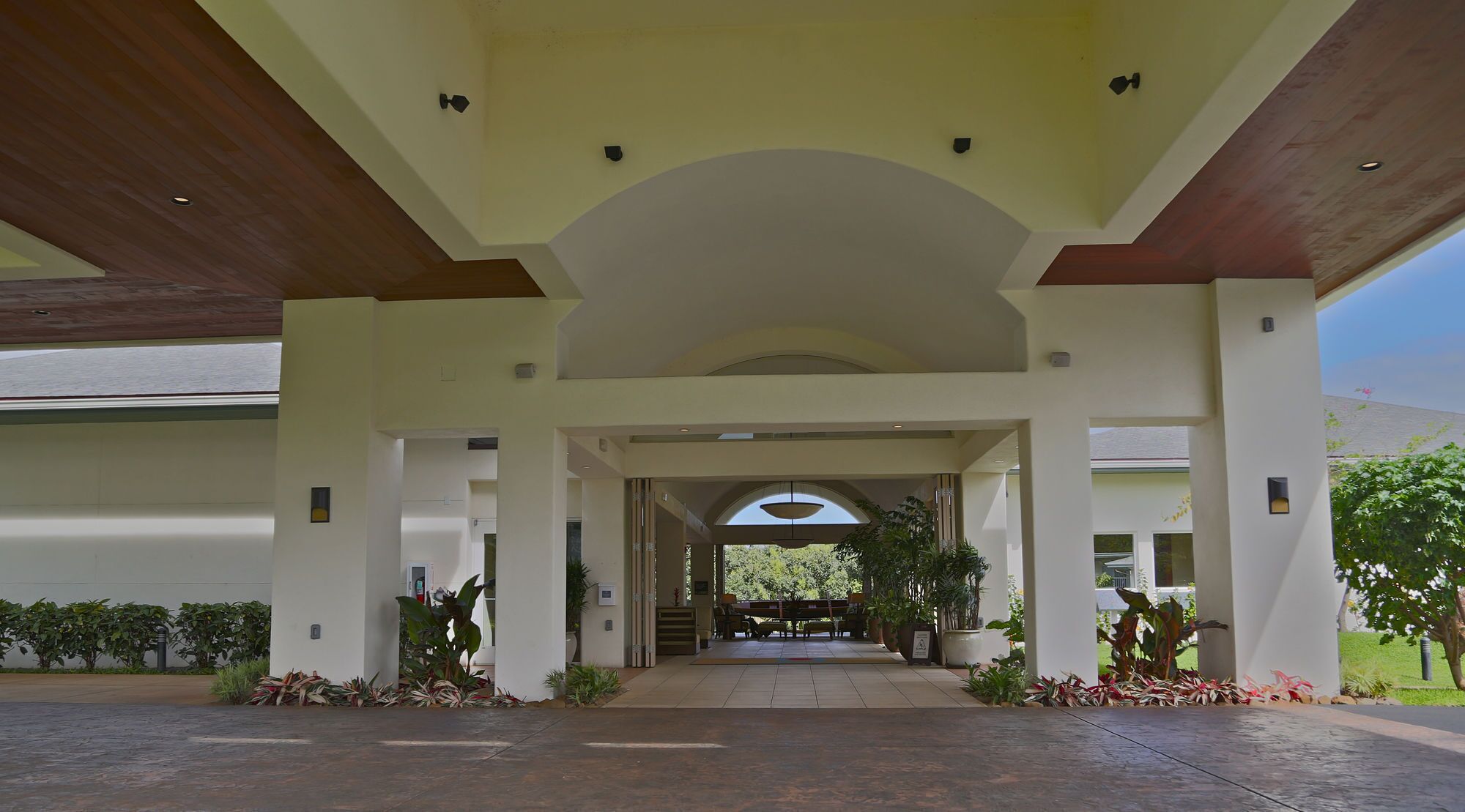 A covered entrance with a central archway, columns, and potted plants.