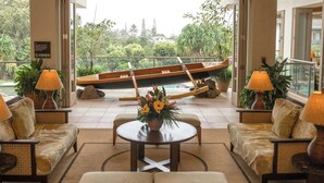 A spacious lobby with a view of a boat, cushioned seating, and a central table with a floral arrangement. - Club Wyndham Bali Hai Villas (Princeville)