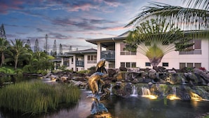 A resort with a water feature, palm trees, and a building with balconies. - Club Wyndham Bali Hai Villas (Princeville)