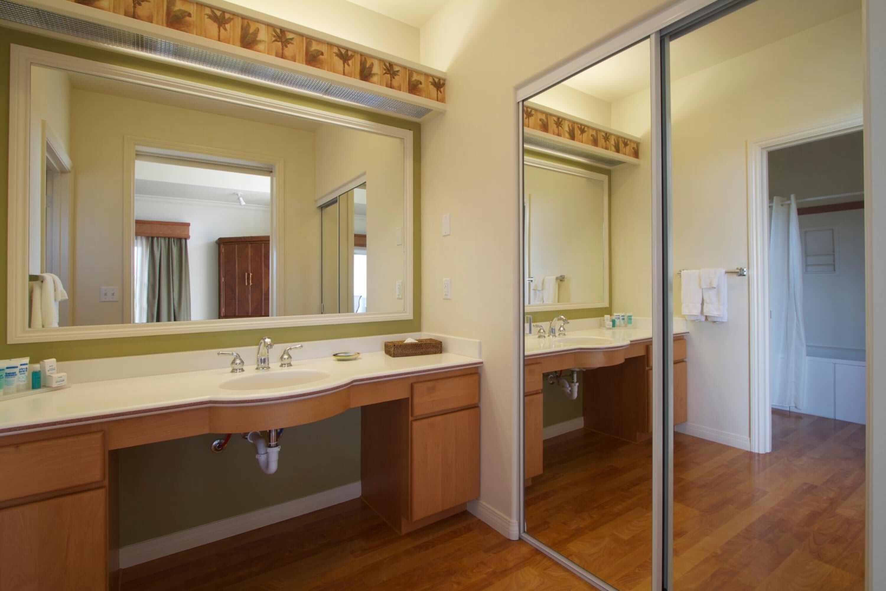 A bathroom with a large mirror, wooden vanity, and a glass shower enclosure.