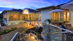 A modern hotel with a glass balustrade, outdoor seating, and a well-lit entrance. - Club Wyndham Bali Hai Villas (Princeville)