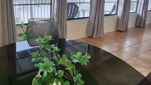 A room with a large window, a welcome sign, and a potted plant on a table.