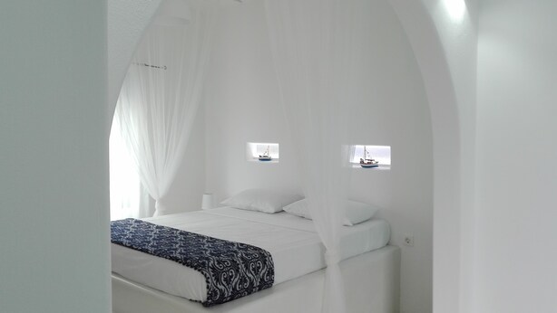 A white room with a bed, a window, and a small table.