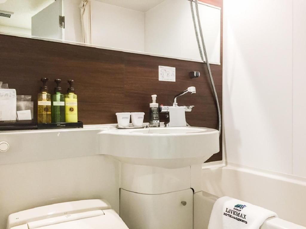 A bathroom with a white sink, a mirror, and toiletries.