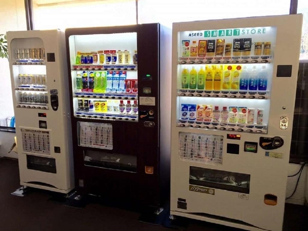 Three vending machines with various beverages and snacks.