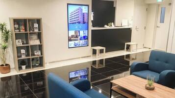 Un moderno vestíbulo de hotel con una recepción, zona de estar y una pantalla digital.