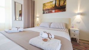 A hotel room with a large bed, two bedside tables, a nightstand, a painting of a forest, and a mirror on the wall. - New picturesque and central penthouse, with a splendid view of the mountains (Torino)