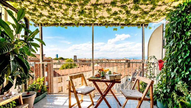 A balcony with a table and chairs, potted plants, and a view of the cityscape. - New picturesque and central penthouse, with a splendid view of the mountains (Torino)