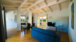 A spacious living area with a blue sofa, wooden flooring, and a kitchen in the background.