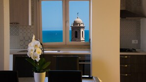 A kitchen with a view of the sea and a bell tower.