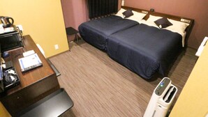 Quarto de hotel com cama, escrivaninha, cafeteira e lixeira.