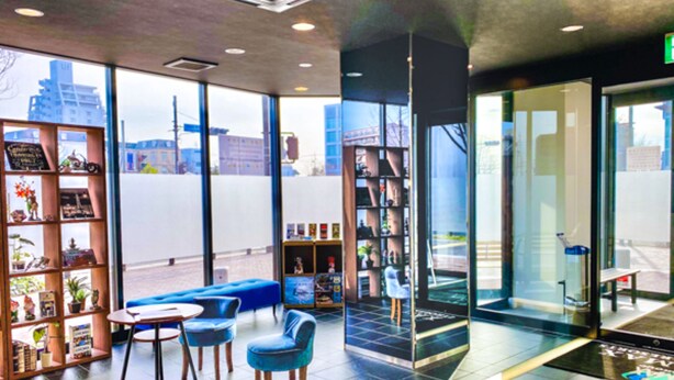 Um interior moderno com área de estar, estante de livros e uma grande janela com vista para a cidade.