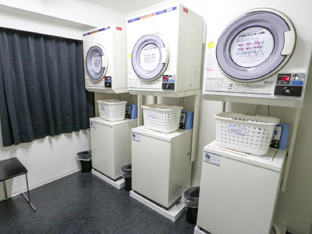 Un cuarto de lavandería con tres lavadoras, cada una con su panel de control y una cesta.