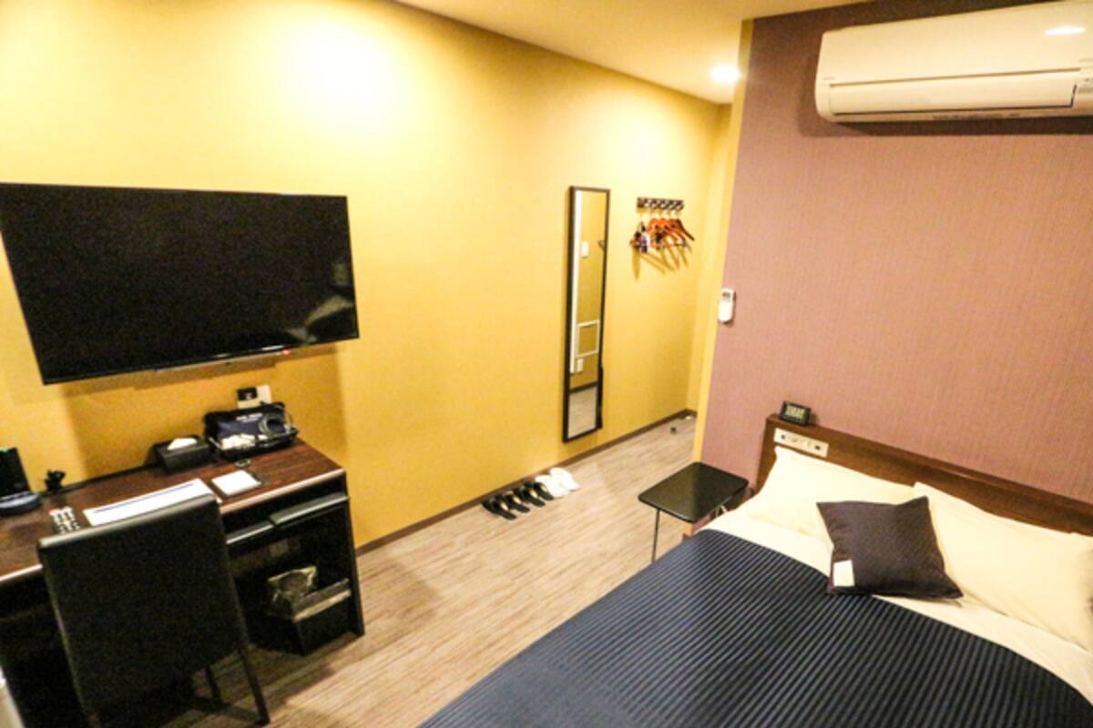 Une chambre d’hôtel équipée d’un lit, d’un bureau, d’une chaise, d’une télévision et d’un appareil de climatisation.