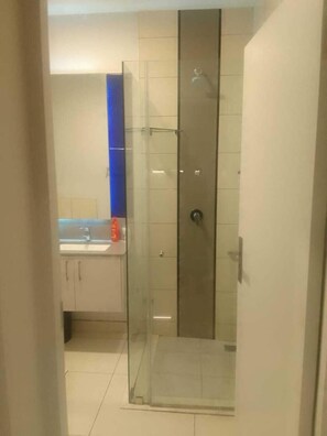 Ein modernes Badezimmer mit einer Duschkabine aus Glas, weißen Fliesenwänden und einer blauen Akzentwand.