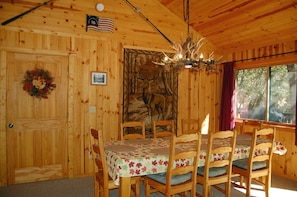 Enjoy a warm, rustic dining experience in this cabin-style accommodation, featuring a beautifully set table and a unique wildlife-themed decor.