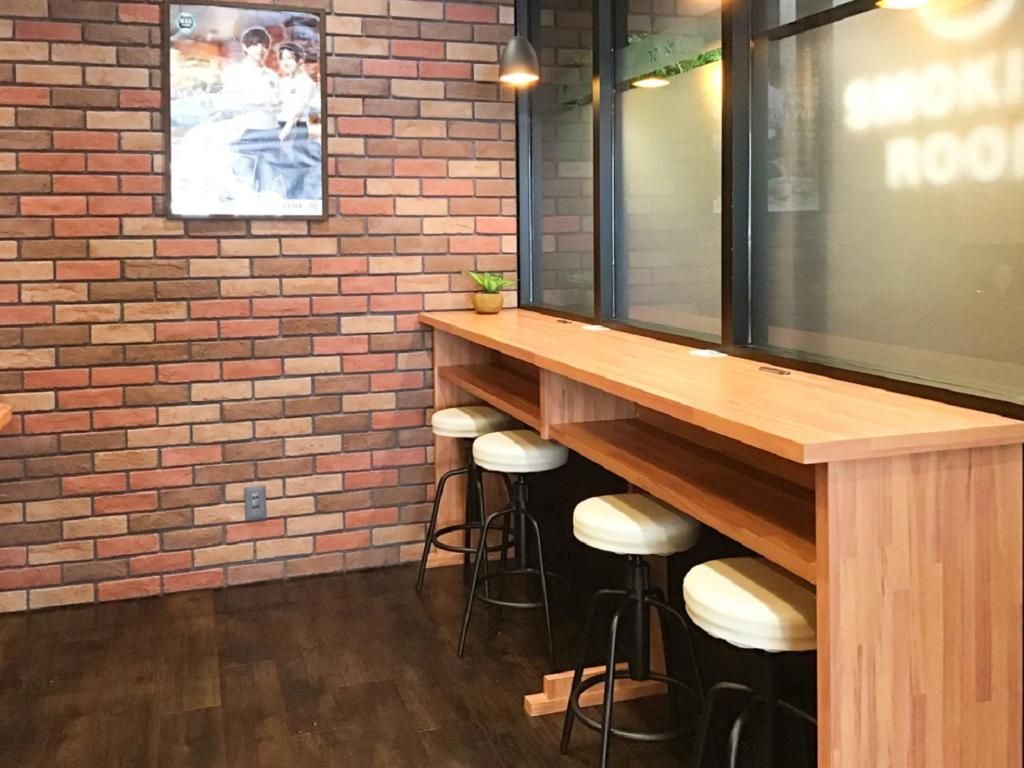 Zona de bar con pared de ladrillo, mostrador de madera y taburetes.