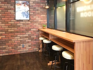 A bar area with a brick wall, wooden counter, and bar stools. - HOTEL LiVEMAX Numazu Ekimae (Numazu)