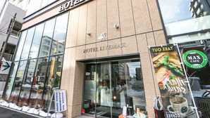 A hotel with a modern facade, large glass windows, and a sign for a cafe. - Hotel Livemax Sapporo Susukino (Sapporo)