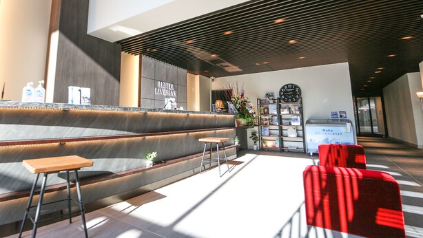 A modern hotel lobby with a reception desk, seating area, and a clock on the wall. - Hotel Livemax Sapporo Susukino (Sapporo)