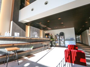 A modern hotel lobby with a reception desk, seating area, and a clock on the wall. - Hotel Livemax Sapporo Susukino (Sapporo)
