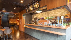A modern restaurant interior with a counter, seating area, and a brick wall backdrop. - Hotel Livemax Sapporo Susukino (Sapporo)