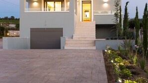 A modern two-story house with a garage, a well-lit entrance, and a landscaped garden. - Anesis Villa, with Private Pool & BBQ, Walking distance to the beach & amenities (Rethymno)